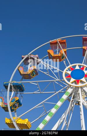 Ruota panoramica contro il cielo blu con colorate cabine vuote Foto Stock