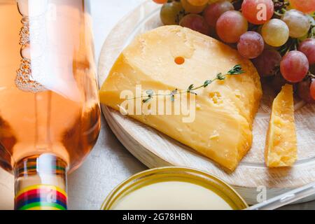 Formaggio olandese gouda stagionato su tavola con erbe di cumino sul tavolo. Formaggio Cheddar con uve, vino rosa, miele. Spuntini al formaggio per un romantico Foto Stock