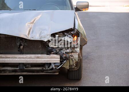 Auto sgualcita si trova su strada con cofano rotto dopo un incidente con nessuno. Auto distrutta che non può essere restaurata e riparata per discarica auto su strada Foto Stock