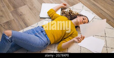 Giovane donna sesaurita dal lavoro sdraiato sul pavimento Foto Stock