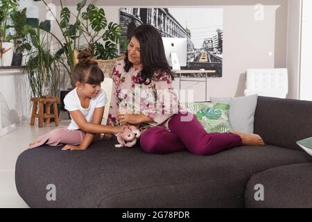 Madre e bambino giocano sul divano nel soggiorno, armoniosamente, divertendosi Foto Stock