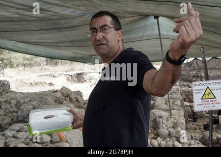 Khirbet un Rai, Israele. 12 luglio 2021. L'archeologo Saar Ganor dell'autorità israeliana per le Antichità sovrintende agli scavi nel sito di Khirbet a Rai, ai piedi della Giudei, precedentemente identificato come la città filistea biblica di Ziklag dai tempi del re Davide, Il luogo in cui Davide trovò rifugio mentre fuggiva dal re Saul e da qui andò a Hebron per essere unto come re. Un'iscrizione d'inchiostro senza precedenti di Proto Canaanite scritto su un vaso di ceramica scoperto porta il nome Jerubbaal, il nome del Giudice Gideon ben Yoash dal Libro dei Giudici. I risultati allo scavo Foto Stock