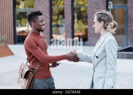 Due partner aziendali o colleghi felici si accolgono gli uni gli altri all'aperto Foto Stock