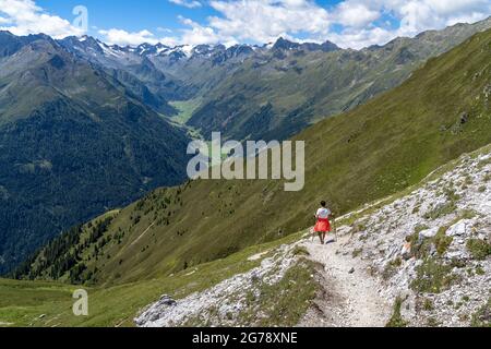 Europa, Austria, Tirolo, Alpi dello Stubai, escursionista femminile in discesa con vista sul pittoresco Oberbergtal nello Stubai Foto Stock