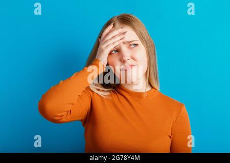 Giovane donna che sperimenta mal di testa sotto stress che tiene la testa. Ritratto emozionale della triste ragazza adolescente con aspettative negative. Emozioni umane di dolore Foto Stock