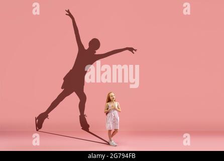 Infanzia e sogno sul grande e famoso futuro. Immagine concettuale con la ragazza e l'ombra del pattinatore femminile figura su corallo rosa parete, sfondo. Foto Stock