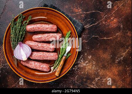 Kofta cruda carne kebabs salsicce su un piatto con erbe. Sfondo scuro. Vista dall'alto. Spazio di copia Foto Stock