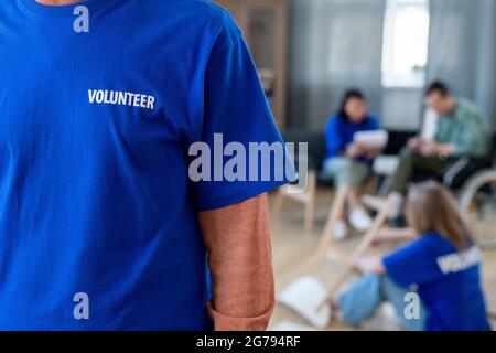 Sezione centrale della volontaria femminile che indossa una t-shirt blu scuro Foto Stock