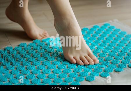 Una donna di mezza età gambe passo sul tappeto di agopuntura massaggio. Massaggio delle feste . Medicina alternativa Foto Stock