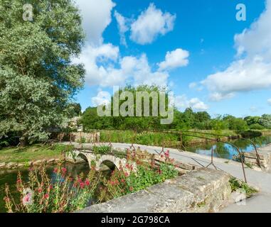 Gran Bretagna, GL Gloucestershire, Bibury vicino Cirencester, ponte sul fiume Coln, storico ponte in pietra, sentiero per Arlington Row. L'artista e scrittore William Morris ha chiamato Bibury 'il villaggio più bello d'Inghilterra'. Foto Stock