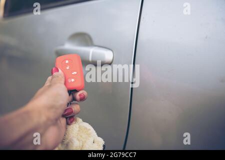 Nel fuoco selettivo delle pressioni di mano sui sistemi di allarme dell'automobile del telecomando.elaborazione trasversale e instragramma di Split tono come processo.con luce del sole Foto Stock