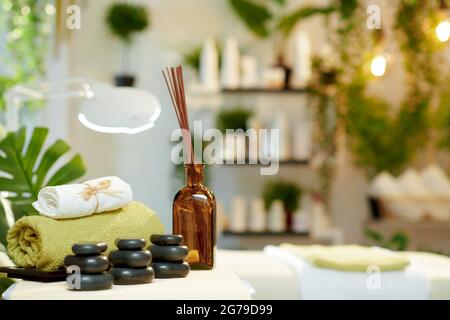 asciugamani, massaggio con pietre calde, oli essenziali e tavolo da massaggio in un moderno salone di bellezza. Foto Stock