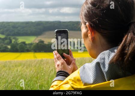 Primo piano di una donna che scatta una foto sul suo smartphone della campagna. Foto Stock