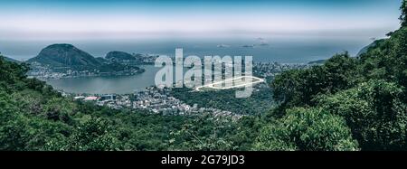 Vista aerea dello skyline di Rio de Janeiro con la Hipódromo da Gávea - la pista da corsa dei cavalli, la Lagoa Rodrigo de Freitas, Ipanema, Leblon e la montagna di pan di zucchero da un punto nella foresta di Tijuca. Foto Stock