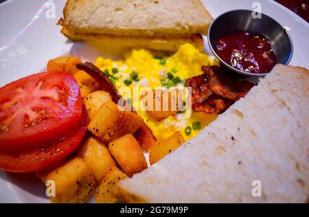 Primo piano della colazione con pane tostato, uova strapazzate e pomodoro. Foto Stock