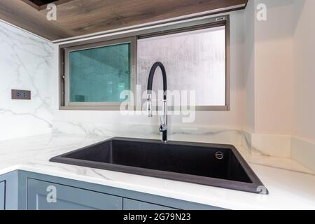 Lussuoso lavandino nero su un piano cucina in marmo. Foto Stock