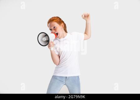 Ritratto di carina ragazza con testa rossa in abito casual che posa isolato su sfondo bianco studio. Concetto di infanzia felice. Bambino soleggiato Foto Stock