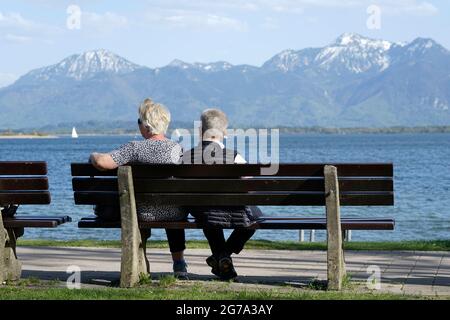 Germania, Baviera, alta Baviera, Chiemgau, Prien, Chiemsee, passeggiata lungo il fiume, coppia in pensione su una panchina del parco Foto Stock