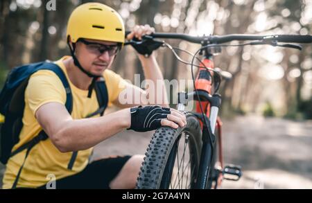 Ciclista uomo che controlla la pressione degli pneumatici Foto Stock