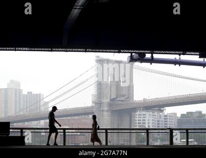 I pedoni camminano con una vista del Ponte di Brooklyn lungo il lato di Manhattan dell'East River a New York City lunedì 12 luglio 2021. Foto di John Angelillo/UPI Foto Stock
