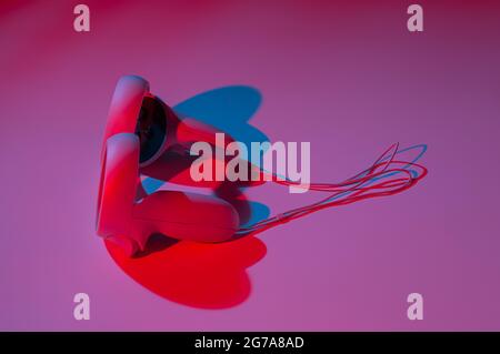 Controller di realtà virtuale per i videogame online e cloud su sfondo bianco con luce al neon. Realtà virtuale, futuro, gadget, concetto di tecnologia. Foto Stock