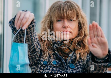 donna con maschera e segnale di stop sulla strada Foto Stock