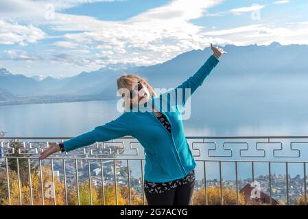 Donna bionda adulta che posa e guarda la macchina fotografica contro il bellissimo paesaggio. Foto Stock