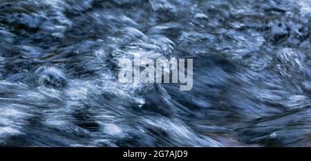 Acqua travagliata con punta di schiuma e spray in bianco, blu chiaro, blu scuro e nero come panorama Foto Stock