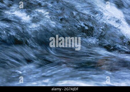 Acqua travagliata con testa di schiuma e spray in bianco, blu chiaro, blu scuro e nero . Foto Stock
