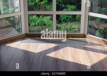 Griglia di protezione integrata nel pavimento per il riscaldamento dei vetri panoramici. Griglia di riscaldamento con ventilazione a pavimento in parquet Foto Stock