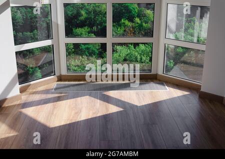 Griglia di protezione integrata nel pavimento per il riscaldamento dei vetri panoramici. Griglia di riscaldamento con ventilazione a pavimento in parquet Foto Stock