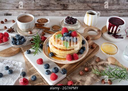 Frittelle con sciroppo d'acero, mirtilli e lamponi per colazione Foto Stock