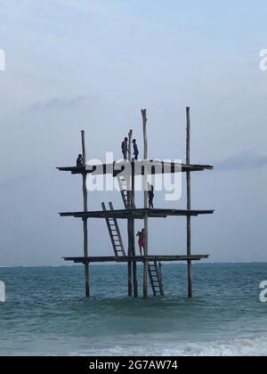 Costa dell'Oceano Indiano. Case di legno su palafitte nel riflusso e flusso. Processo di costruzione. Isola di Zanzibar. Africa. Vista tipica. Foto Stock