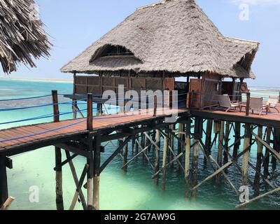 Costa dell'Oceano Indiano. Case di legno su palafitte nel riflusso e flusso. Isola di Zanzibar. Africa. Vista tipica. Foto Stock