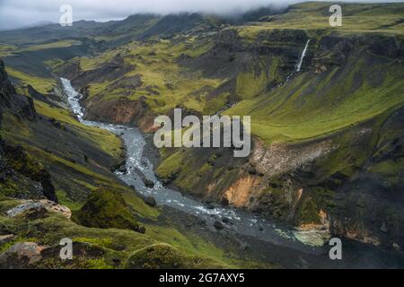 Paesaggio islandese della valle dell'altopiano e del fiume Fossa con il flusso d'acqua blu e verdi colline e scogliere coperte di muschio. Islanda del Sud Foto Stock