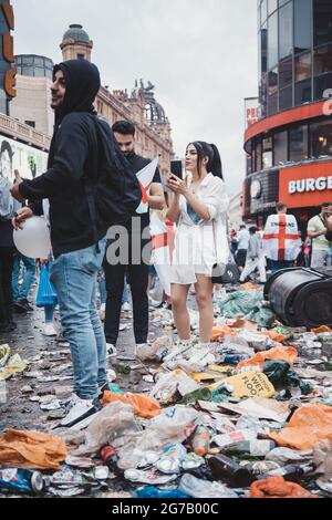 Londra | UK - 2021.07.12: Bella ragazza che scatta foto di tifosi di calcio a Leicester Square coperta di spazzatura Foto Stock