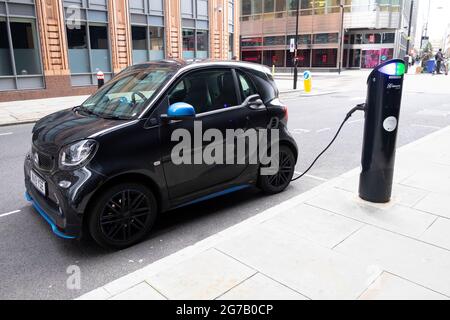 Black Smart ForFour piccola auto elettrica che si ricarica presso la stazione di ricarica in una strada nella città di Londra UK KATHY DEWITT Foto Stock