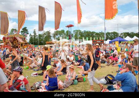 Festivalgoers godendo del sole estivo in un gestival in Inghilterra. Womad festival, Chharlton Park, Malmesbury Wiltshire Foto Stock
