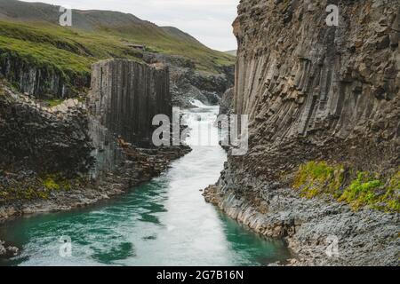 Il canyon di basalto di Studlagil, con rare formazioni vulcaniche di colonna di basalto e il fiume blu proveniente dall'acqua di fusione del ghiacciaio. Islanda. Foto Stock