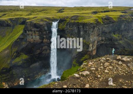 Vista aerea di una donna con zaino godendo la cascata di Haifoss delle Highlands Islanda Foto Stock