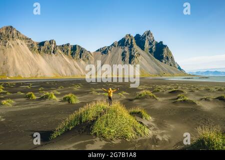 Islanda. Vista aerea dell'escursionista con zaino sulle dune di sabbia nera sul promontorio di Stokksnes, sulla costa sud-orientale islandese con Vestrahorn. Europa. Foto Stock