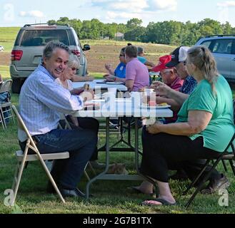 L'ex governatore del Kansas, il Dr. Jeff Colyer, ride di una barzelletta mentre mangia a un tavolo con i membri della Lyon County GOP al loro picnic annuale. Foto Stock