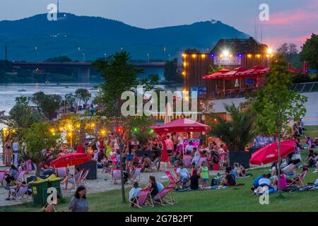 Vienna, area ricreativa Copa Beach sul fiume Neue Donau (nuovo Danubio), persone sul prato, bar, vista su Wienerwald e Millennium Tower nel 22. Donaustadt, Vienna, Austria Foto Stock