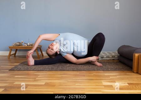 Donna caucasica incinta seduta in yoga asana Foto Stock