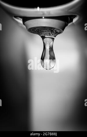 Eliminare le gocce d'acqua che cadono dal rubinetto. Fotografia in bianco e nero a contrasto. Foto Stock