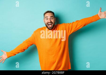 un uomo in un maglione arancione allarga le gambe a spalla e gesti con le  mani Foto stock - Alamy