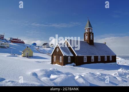 Chiesa di legno nel paesaggio invernale, case e fiordo sullo sfondo, Chiesa di Sion, Ilulissat, Groenlandia, Danimarca Foto Stock