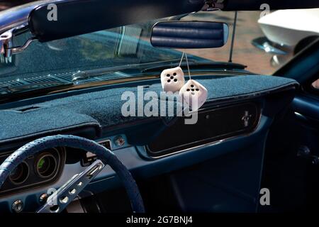 Un paio di dadi decorativi sfumati che si tramandano dallo specchio retrovisore di un'auto d'epoca in mostra in occasione di una mostra di auto classica a Santa Fe, New Mexico. Foto Stock