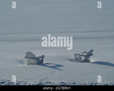 Sedie bianche isolate contro White Snow Lakeside Foto Stock