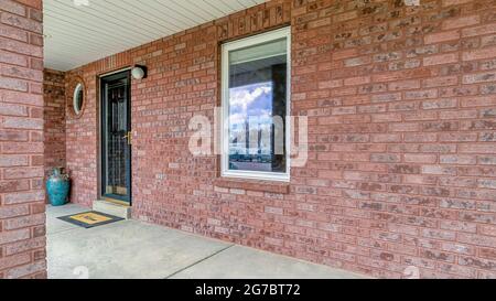 Pano spazioso e aperto avvolge intorno portico di casa in cemento con parete esterna in mattoni Foto Stock
